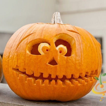 Carved Jack O' Lantern pumpkin with round eyes and toothy smile on outdoor surface